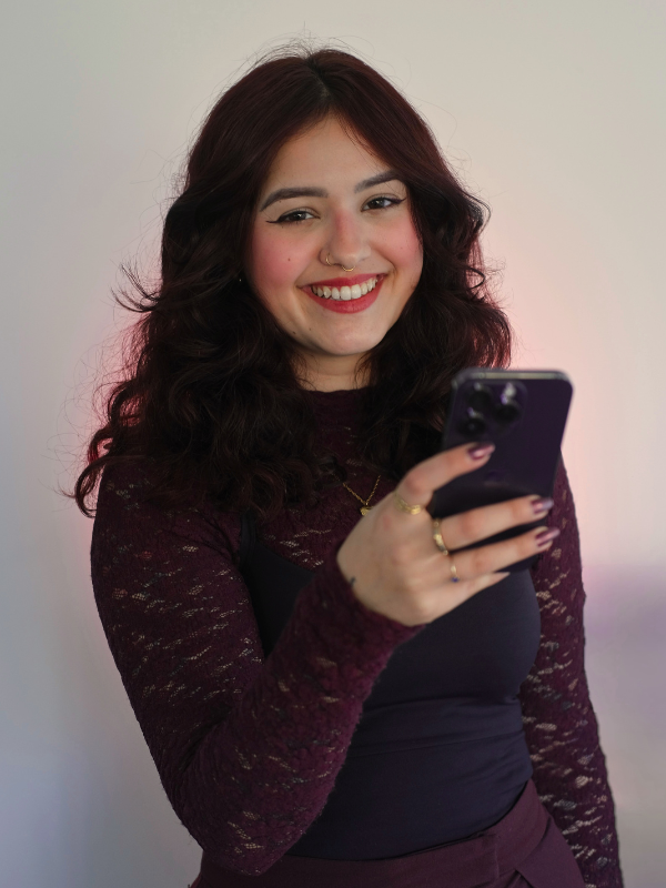 Natália Volkmer sorrindo, celular na mão